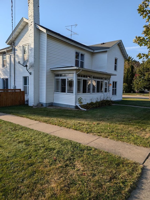 back of house with a yard and a sunroom