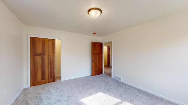 unfurnished bedroom featuring a closet and light colored carpet