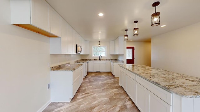 kitchen featuring white cabinets, sink, decorative light fixtures, light stone counters, and stainless steel appliances