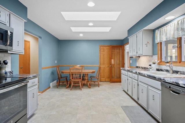 kitchen with a skylight, appliances with stainless steel finishes, sink, and tasteful backsplash