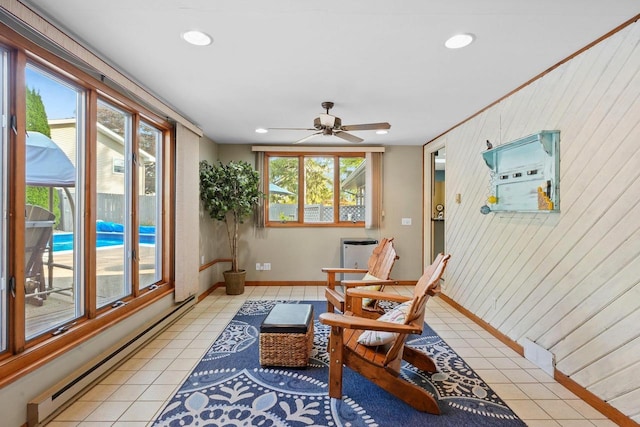 sitting room featuring ceiling fan, wood walls, light tile patterned floors, and baseboard heating