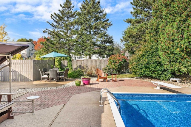 view of swimming pool with a wooden deck, a patio, and a diving board