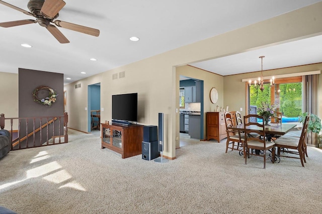 carpeted living room with ceiling fan with notable chandelier