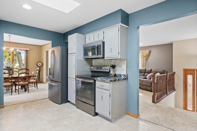 kitchen featuring light tile patterned floors, decorative light fixtures, appliances with stainless steel finishes, a notable chandelier, and decorative backsplash