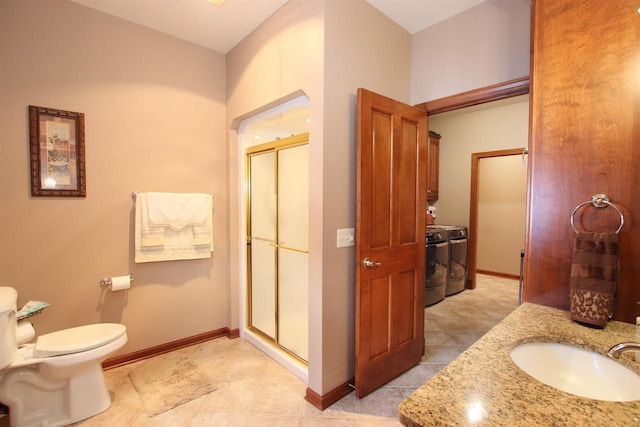 bathroom featuring vanity, washing machine and dryer, toilet, and walk in shower