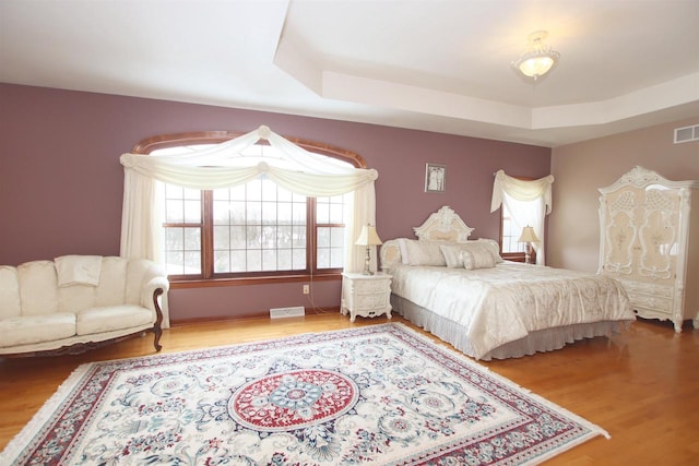 bedroom with hardwood / wood-style flooring and a tray ceiling