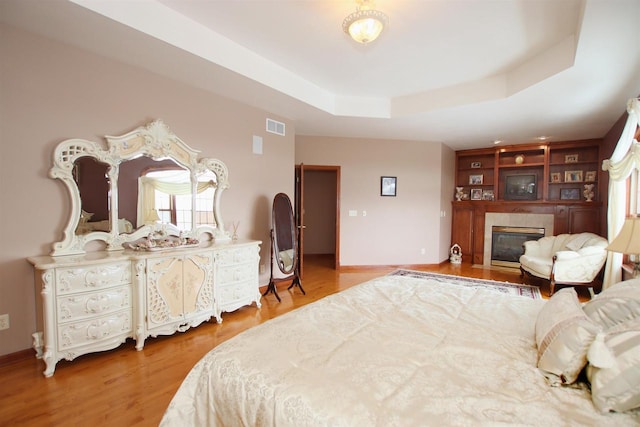 bedroom with a tray ceiling and wood-type flooring