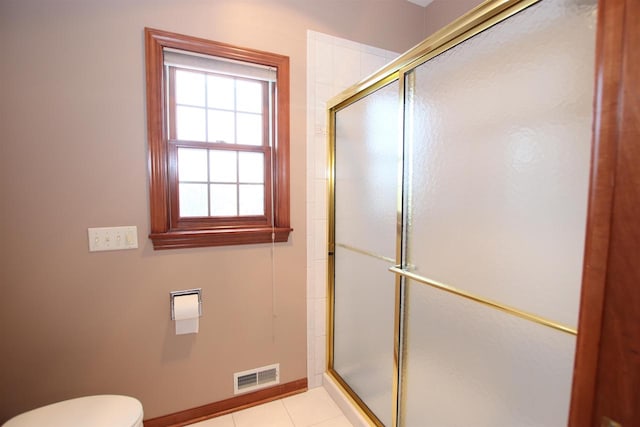 bathroom with toilet, tile patterned floors, and a shower with shower door