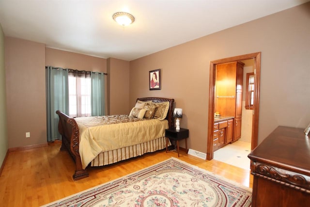 bedroom featuring light hardwood / wood-style flooring and ensuite bath