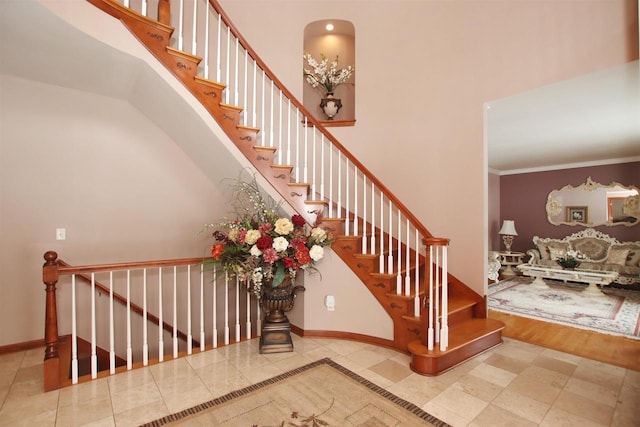 staircase with hardwood / wood-style floors, ornamental molding, and a high ceiling