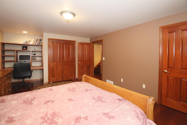 bedroom featuring built in desk, dark wood-type flooring, and a closet