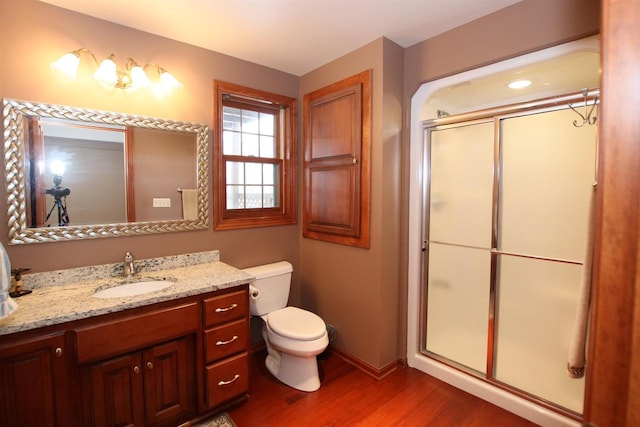 bathroom featuring a shower with door, vanity, wood-type flooring, and toilet