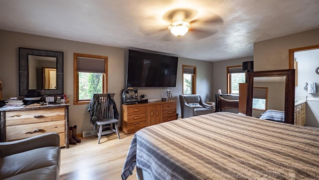 bedroom with ceiling fan, ensuite bathroom, light hardwood / wood-style floors, and multiple windows