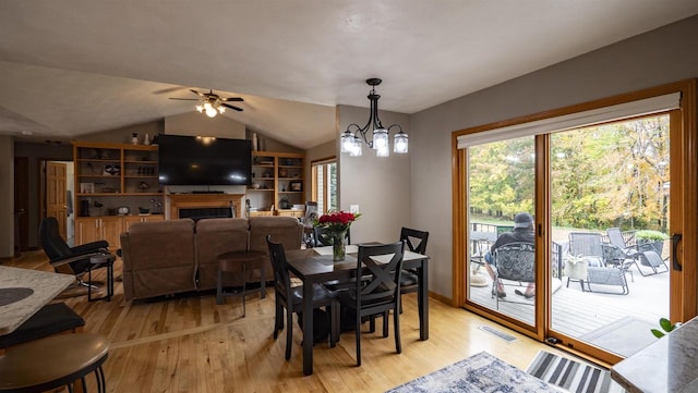 dining area featuring ceiling fan with notable chandelier, light wood-type flooring, and lofted ceiling