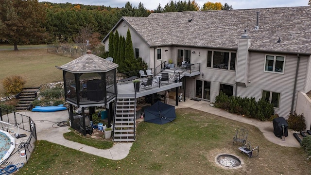 rear view of house featuring a gazebo, a fire pit, a swimming pool, a lawn, and a patio area