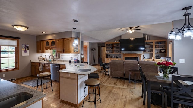 kitchen with lofted ceiling, sink, pendant lighting, a kitchen bar, and dishwasher