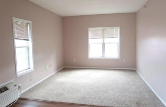 carpeted empty room with a wall mounted AC and a wealth of natural light