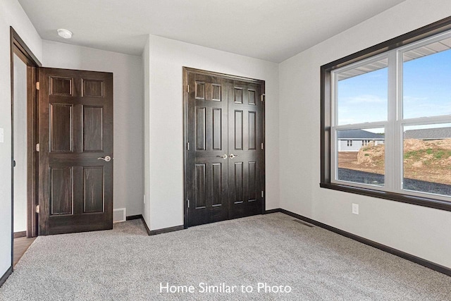 unfurnished bedroom with a closet and light colored carpet