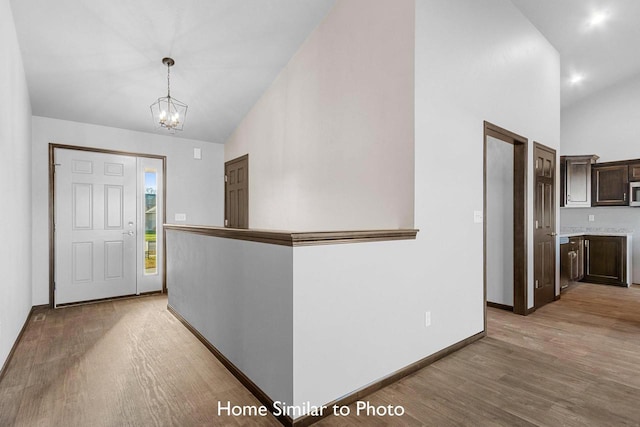 entrance foyer with an inviting chandelier, light wood-type flooring, and high vaulted ceiling