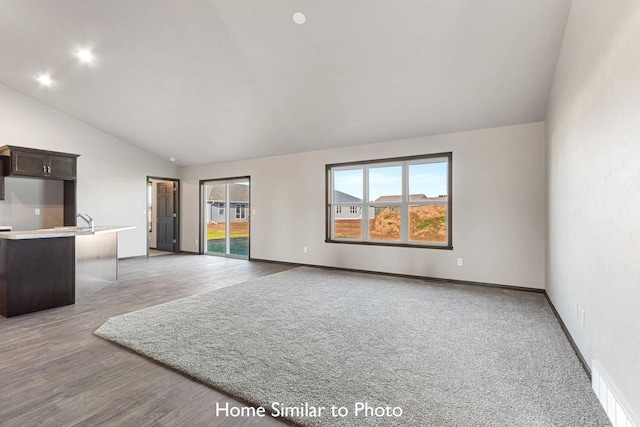 unfurnished living room with lofted ceiling, light wood-type flooring, and sink