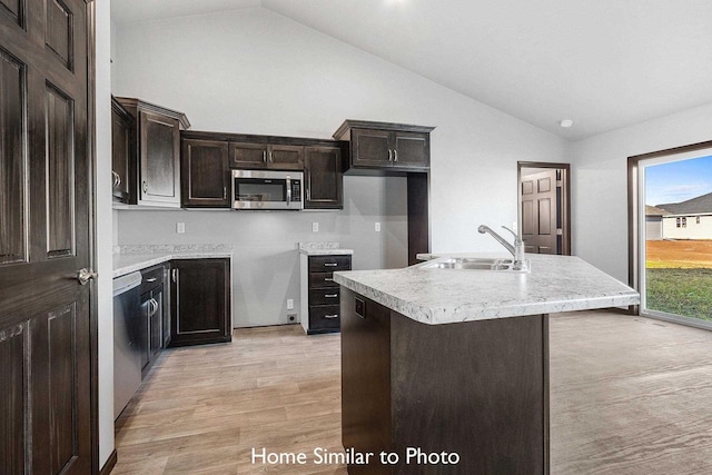 kitchen with lofted ceiling, stainless steel appliances, sink, light hardwood / wood-style flooring, and a center island with sink