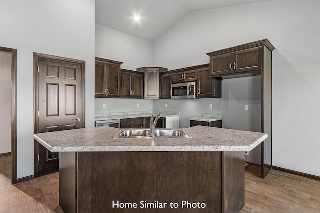 kitchen with a center island with sink, dark brown cabinets, dark wood-type flooring, and sink