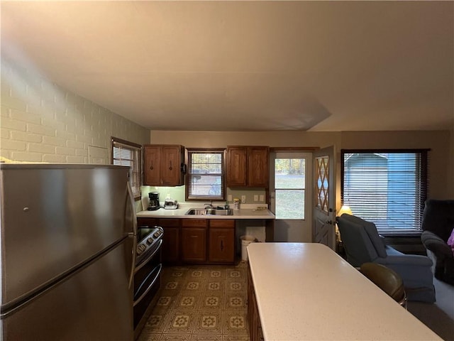 kitchen featuring sink, stainless steel appliances, and brick wall