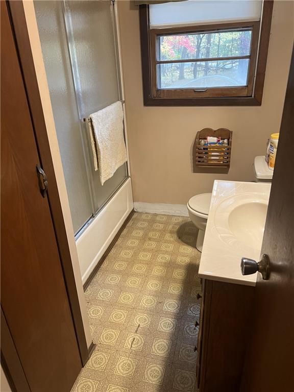 full bathroom featuring enclosed tub / shower combo, vanity, and toilet