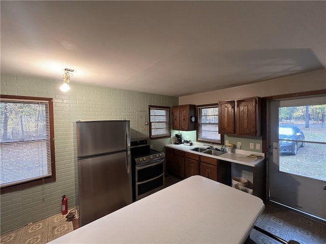 kitchen with sink, stainless steel appliances, and brick wall