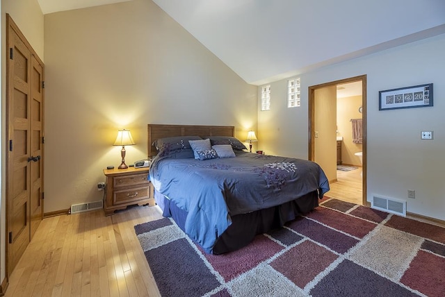 bedroom featuring vaulted ceiling, light hardwood / wood-style flooring, and ensuite bath