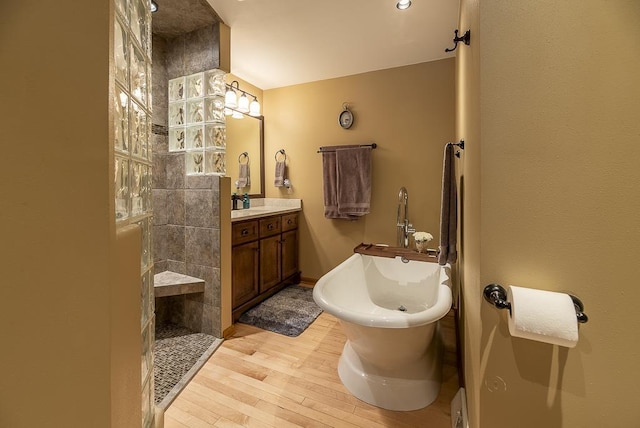 bathroom featuring plus walk in shower, hardwood / wood-style floors, and vanity