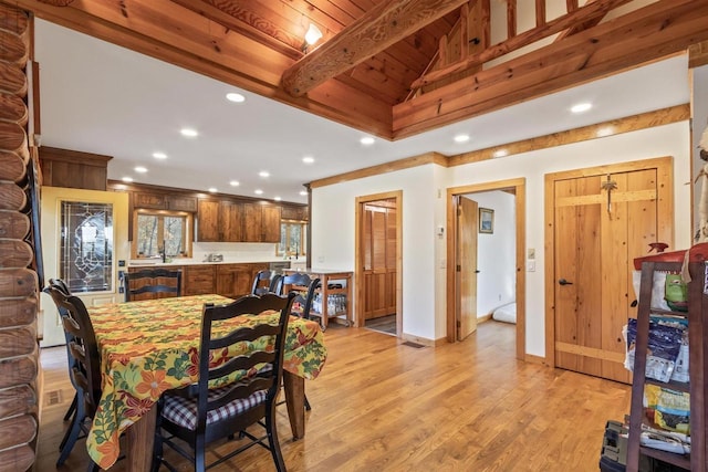 dining room with lofted ceiling with beams, wood ceiling, and light wood-type flooring