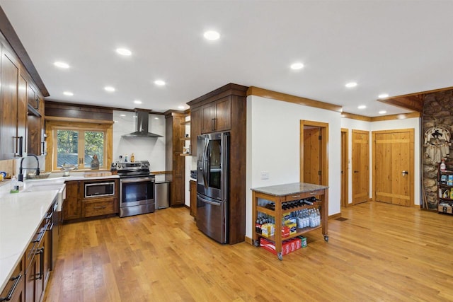 kitchen with wall chimney exhaust hood, sink, stainless steel appliances, and light hardwood / wood-style floors