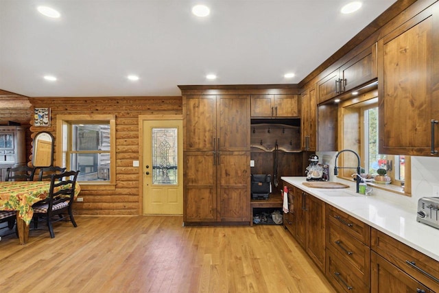 kitchen with light hardwood / wood-style floors, sink, and rustic walls