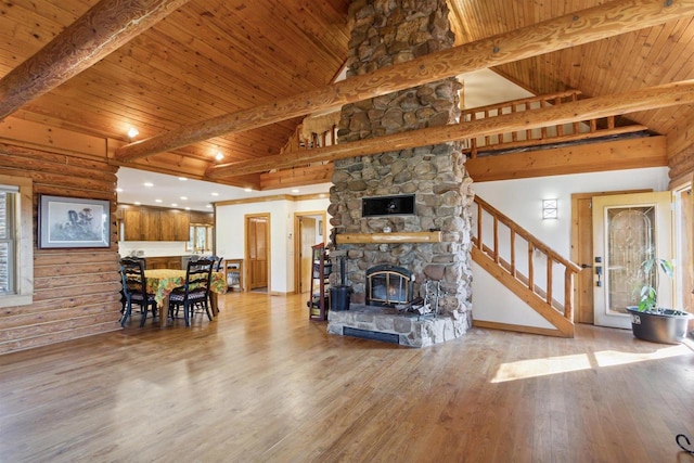 living room featuring a stone fireplace, light hardwood / wood-style flooring, beam ceiling, and wood ceiling