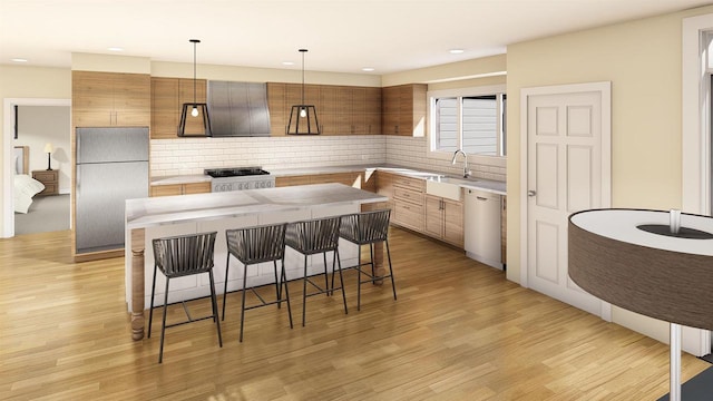 kitchen with appliances with stainless steel finishes, decorative light fixtures, a kitchen island, and light wood-type flooring