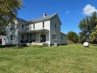 rear view of house featuring a lawn and covered porch