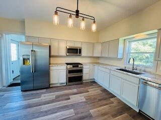 kitchen featuring decorative light fixtures, stainless steel appliances, dark wood-type flooring, and sink