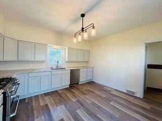 kitchen with hanging light fixtures, sink, white cabinetry, hardwood / wood-style flooring, and stainless steel appliances