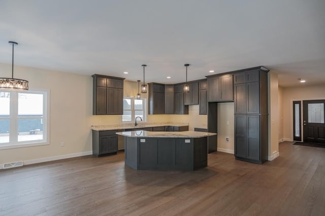 1003 E 10th St, Merrill, WI 54452 - kitchen featuring a sink, a kitchen island, dark wood-style flooring, baseboards, and recessed lighting