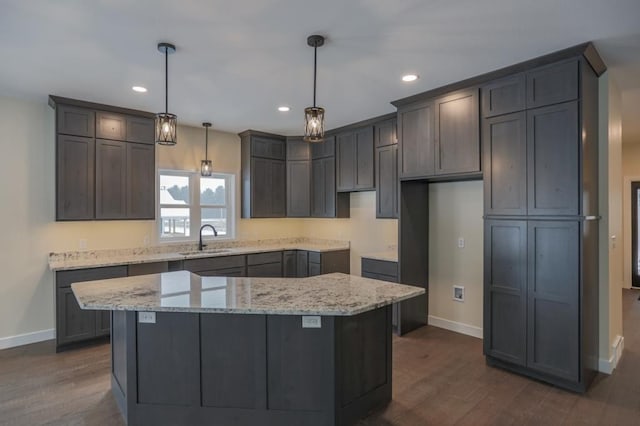 1003 E 10th St, Merrill, WI 54452 - kitchen with a sink, baseboards, dark wood-type flooring, light stone countertops, and a center island