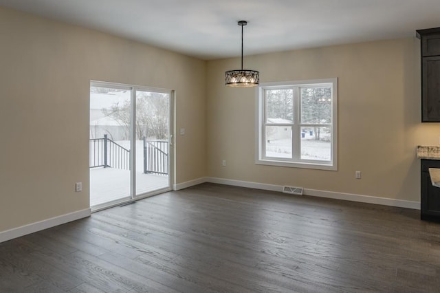 1003 E 10th St, Merrill, WI 54452 - unfurnished dining area with healthy amount of natural light, dark wood finished floors, a chandelier, and baseboards