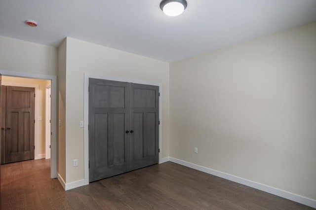 1003 E 10th St, Merrill, WI 54452 - unfurnished bedroom featuring dark wood finished floors, baseboards, and a closet