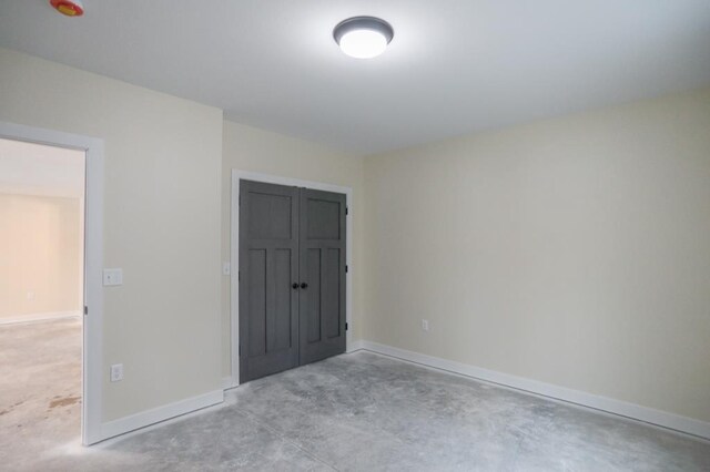 1003 E 10th St, Merrill, WI 54452 - unfurnished bedroom featuring unfinished concrete flooring, baseboards, and a closet
