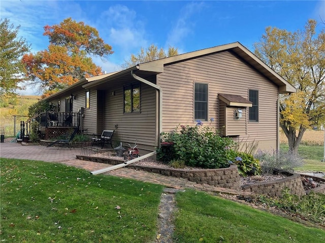 view of property exterior with a deck, a yard, and a patio