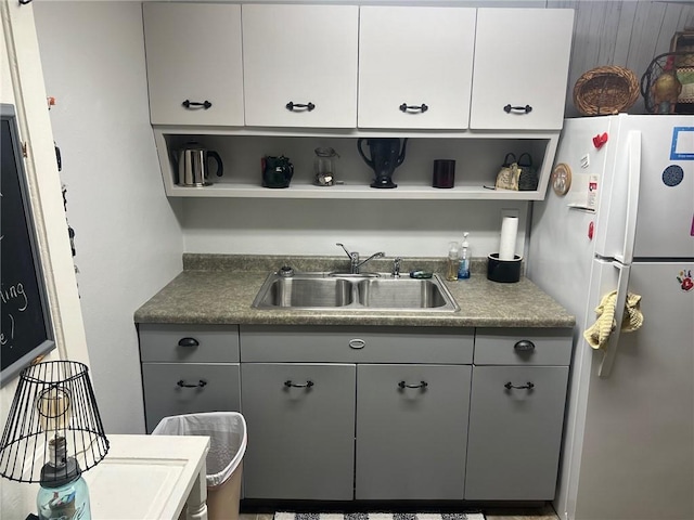 kitchen featuring white refrigerator, gray cabinets, white cabinets, and sink