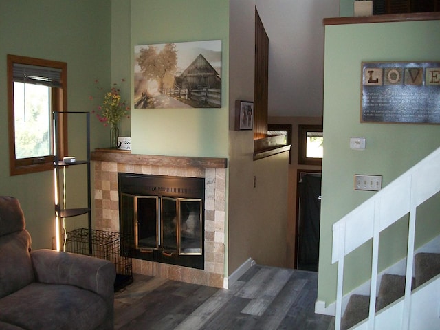 living room featuring a towering ceiling, hardwood / wood-style flooring, and a tiled fireplace