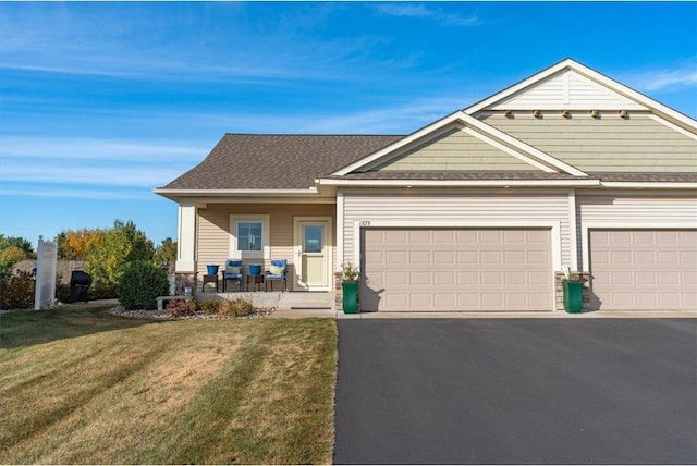 view of front of home featuring covered porch, a front yard, and a garage