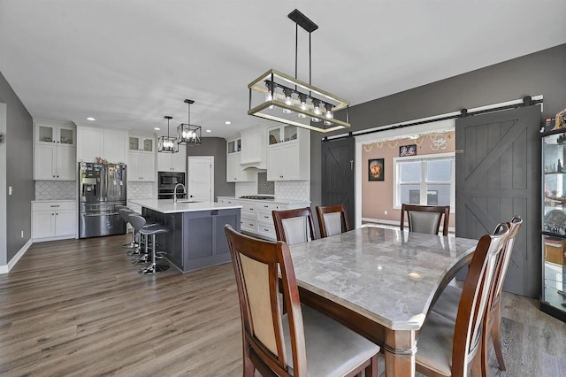 dining room with sink, dark wood-type flooring, and a barn door