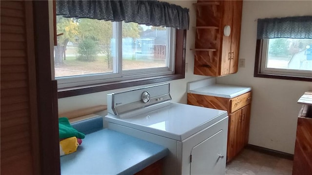 laundry room featuring a healthy amount of sunlight, washer / clothes dryer, and cabinets